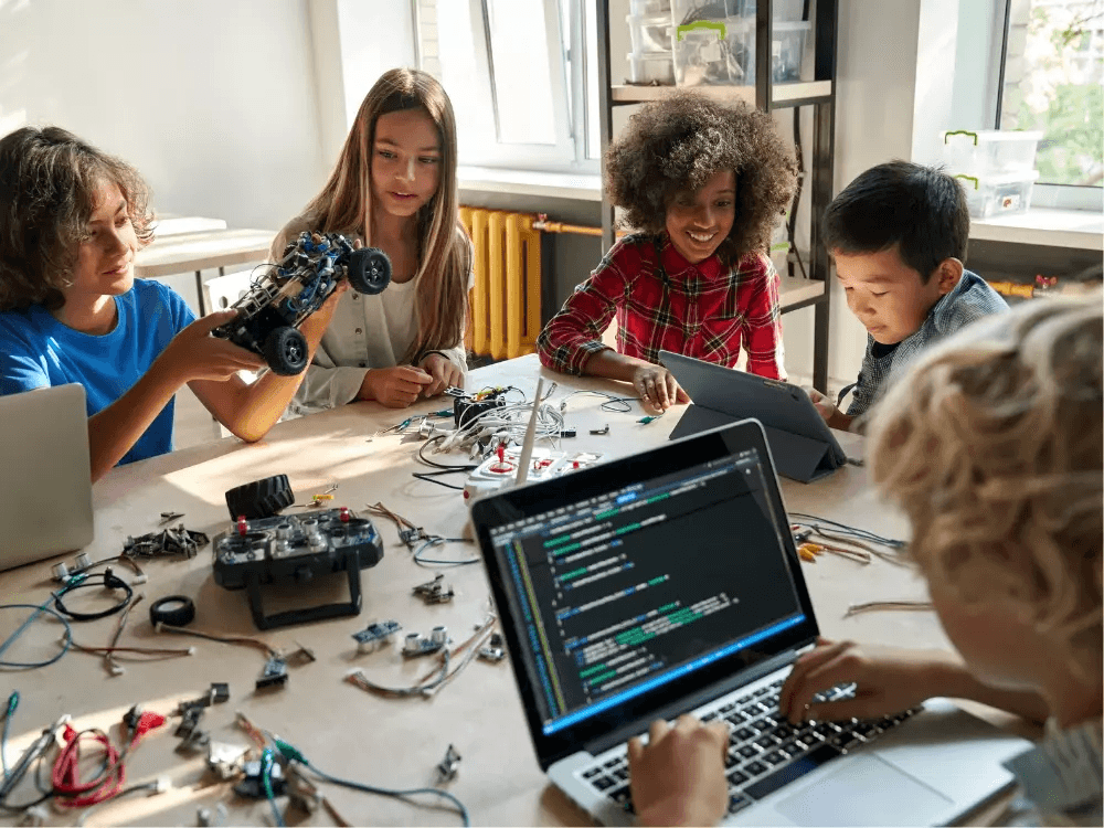A group of students coding and assembling robots around a workshop table